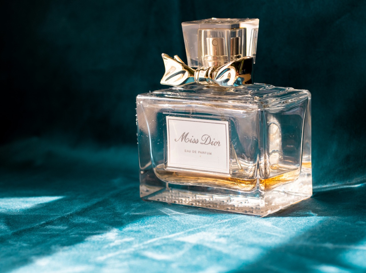A perfume bottle photographed on deep teal velvet